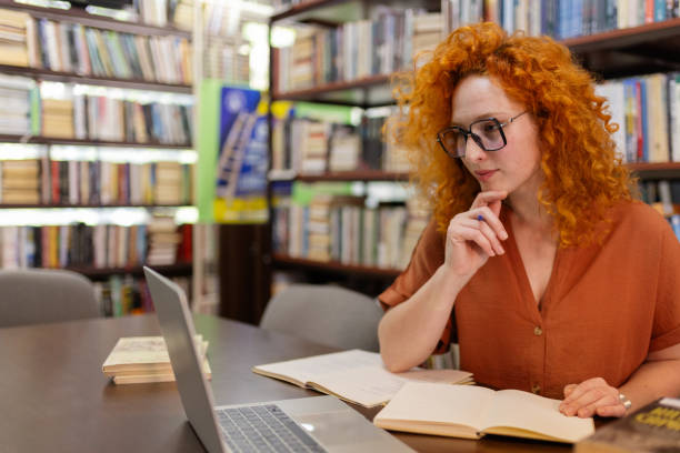 istock Focused Female Student Writing in Cozy Library 2190441423