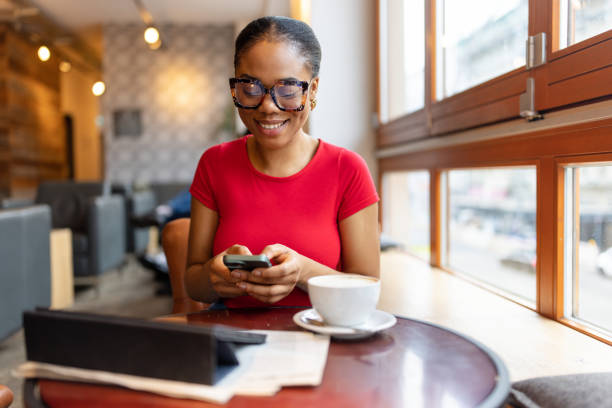 istock Smiling woman in glasses enjoying coffee and using smartphone 2190442034