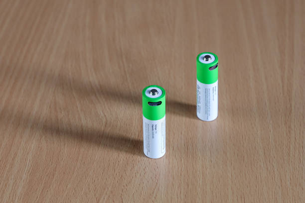 Two rechargeable batteries on wood close-up, green energy