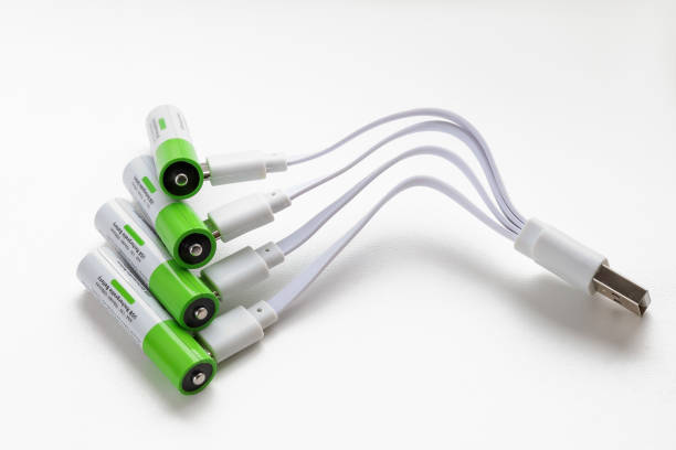 istock Four rechargeable AAA batteries with plugged in USB plugs charging wires, close-up on white background 2190444801