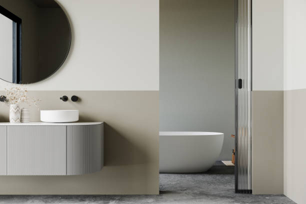istock Modern minimalist bathroom interior, modern bathroom cabinet, white sink, wooden vanity, interior plants, bathroom accessories, bathtub and white and green tones walls, concrete floor. 2190444906