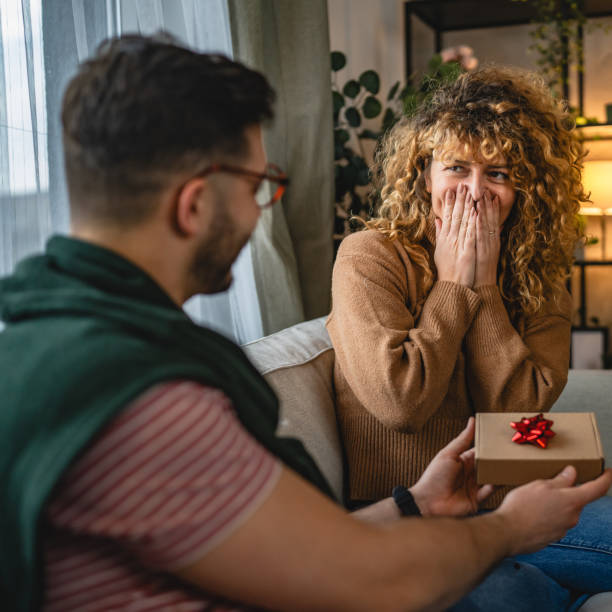 istock Boyfriend surprise his girlfriend with gift box while sit on sofa 2190448029