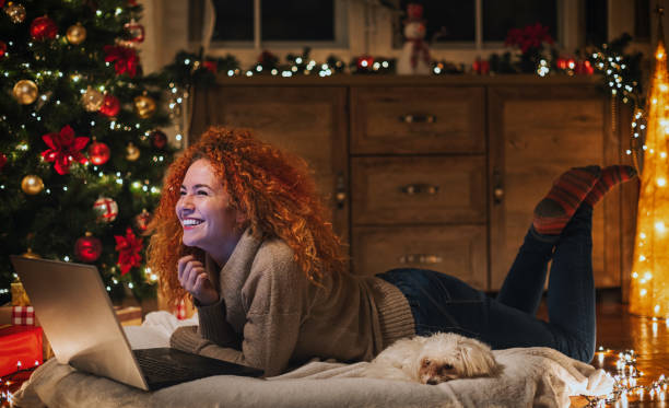 istock Young beautiful woman enjoying at home while using laptop in a cozy Christmas atmosphere 2190448671
