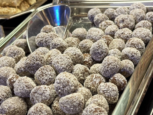 istock Coconut-coated chocolate truffles on display in metal tray at dessert buffet 2190449003