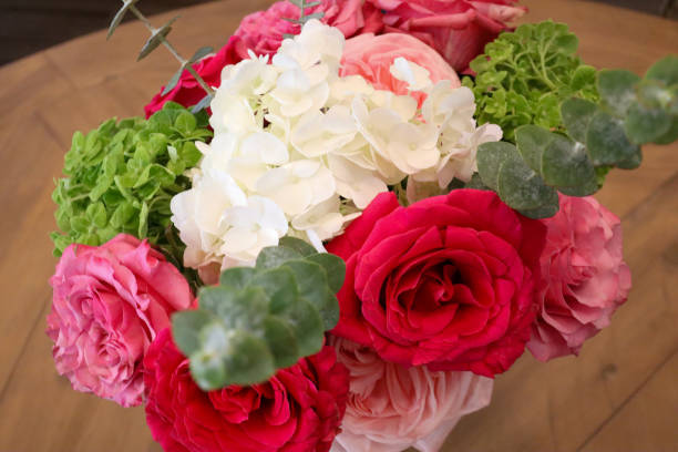 istock A stunning bouquet of vibrant red and pink roses, soft white hydrangeas, green hydrangeas, and eucalyptus leaves, arranged with delicate textures and bold colors on a wooden table. 2190451031