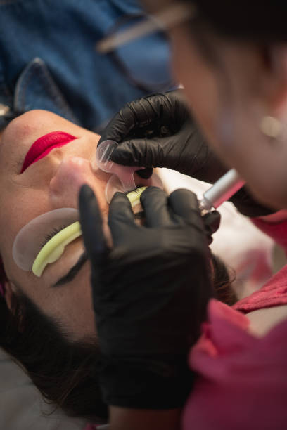 Beautician carefully applying eyelash lift treatment to a client in a beauty salon