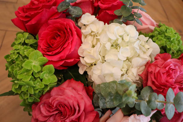 istock A vibrant bouquet featuring red and pink roses, white hydrangeas, lush green foliage, and eucalyptus leaves, artfully arranged for a stunning floral centerpiece. 2190453604