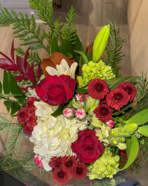 istock A festive bouquet featuring red roses, white hydrangeas, red chrysanthemums, green accents, and lush evergreen sprigs, perfect for the holiday season. 2190455104