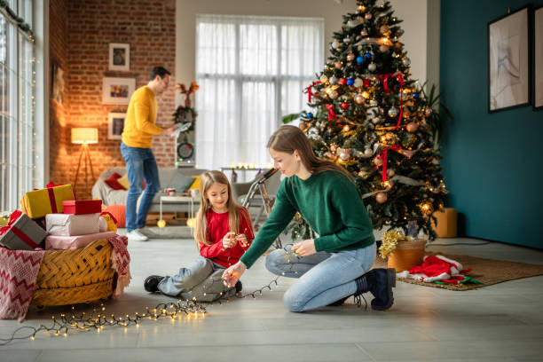 istock Family decorating their home and Christmas tree with festive decorations and lights 2190455431