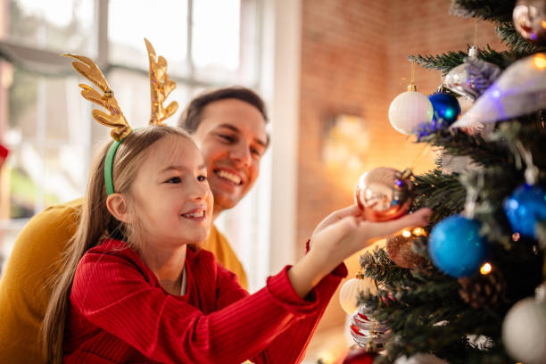 Father Helps Daughter Decorate Christmas Tree Together at Home