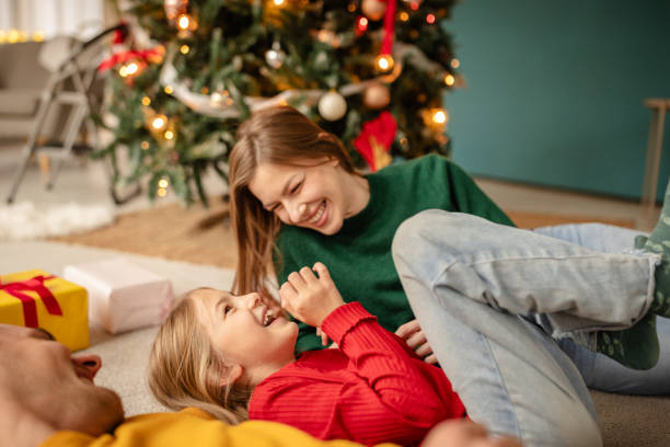 istock Happy family enjoying Christmas together by a decorated tree 2190457675
