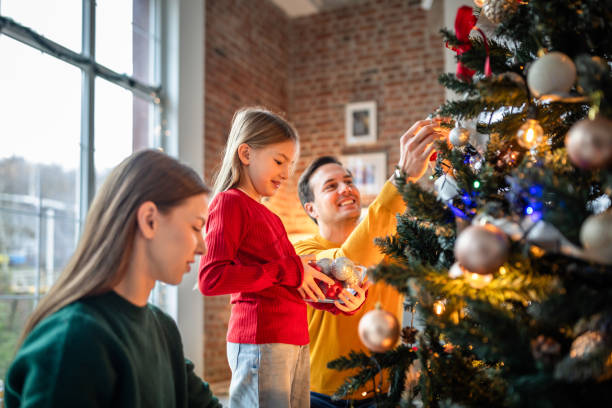 istock Family decorating a Christmas tree together in a cozy home interior 2190459719
