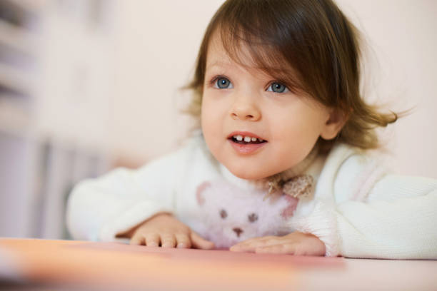 little child girl sitting at the table at home, child development.