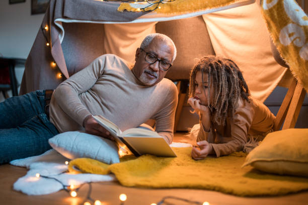 istock Grandfather and Grandson Reading Book Inside Cozy Fort 2190459889