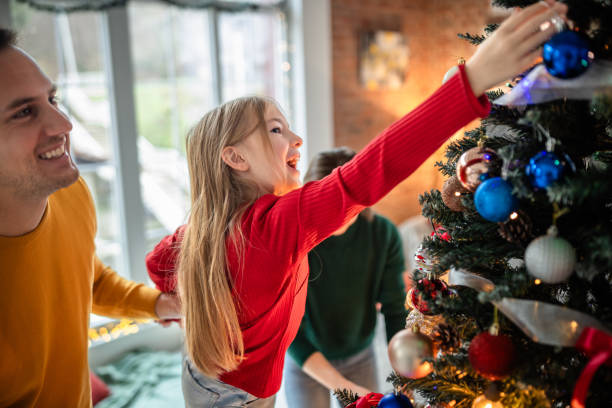 istock Family decorating a vibrant Christmas tree inside a cozy home 2190460579