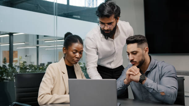 istock Arab man coach leader boss talking about mistake explain Indian teacher mentor teaching interns managers employees use online app help with software diverse team looking laptop discussing project 2190460608
