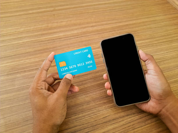 istock Hands Holding Credit Card and Smartphone on Wooden Table 2190465309