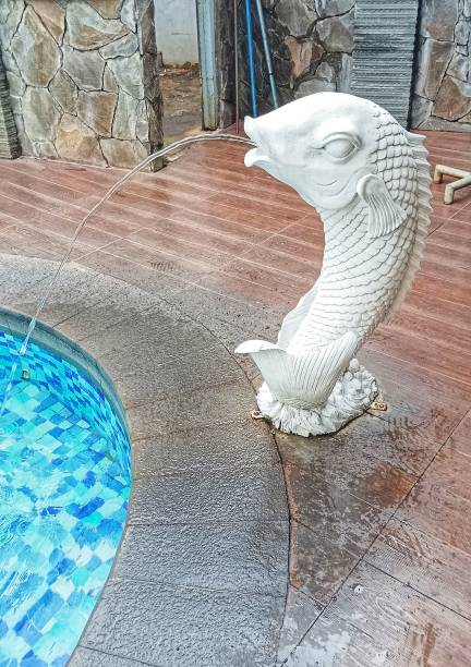 istock fish statue with fountain ornaments by blue swimming pool 2190469705
