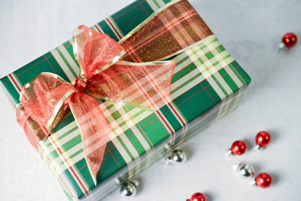 istock Festive plaid gift with glittery red bow surrounded by ornaments 2190475136