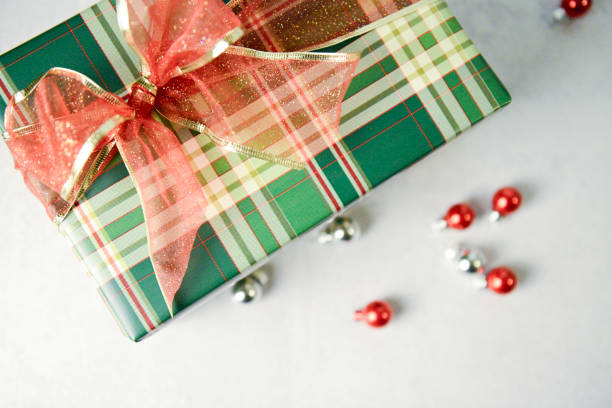 istock Plaid gift with glittery red bow surrounded by shiny ornaments. 2190475138