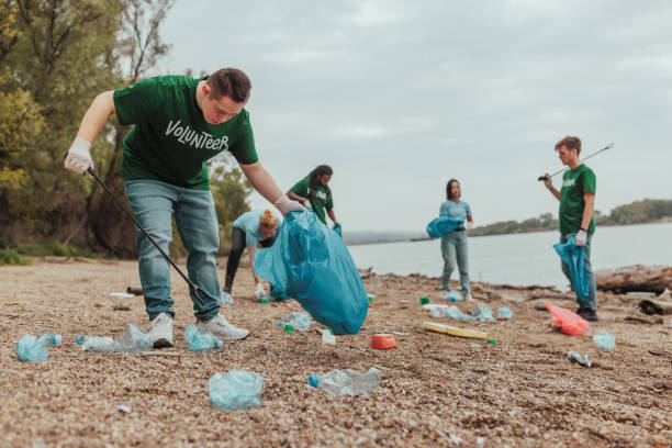 istock Volunteers picking up trash on river bank: cleaning up plastic bottles 2190476171