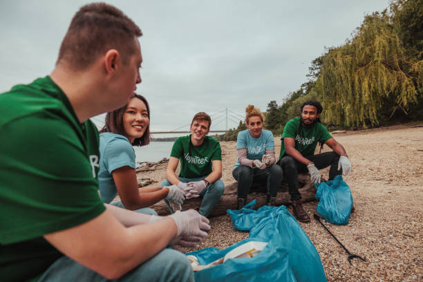Volunteers collecting trash on riverbank: teamwork for a clean environment