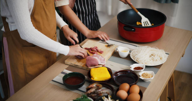 istock Two beautiful Asian women talk while cooking together in a bright room. 2190479168