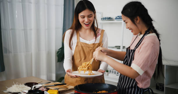istock Two beautiful Asian women talk while cooking together in a bright room. 2190479744