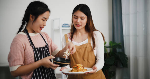 istock Two beautiful Asian women talk while cooking together in a bright room. 2190479748