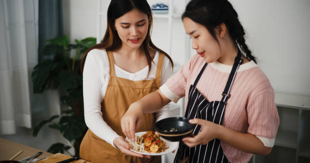 istock Two beautiful Asian women talk while cooking together in a bright room. 2190479758