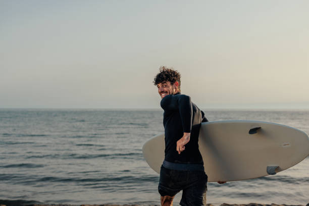 istock Man running into the sea with a surfboard 2190480352