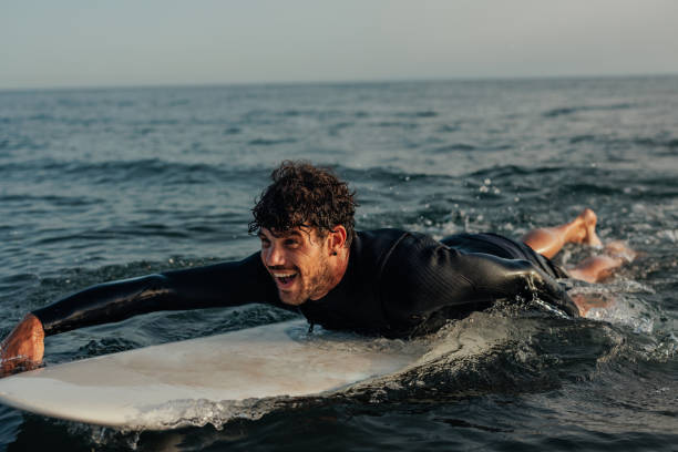 istock Close up of a surfer lying on a surfboard in the water 2190480355