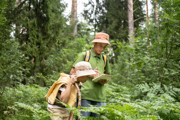 istock Two children boys with backpack looking examining plants through magnifying glass while exploring forest nature and environment on sunny day during outdoor ecology school lesson. 2190480579
