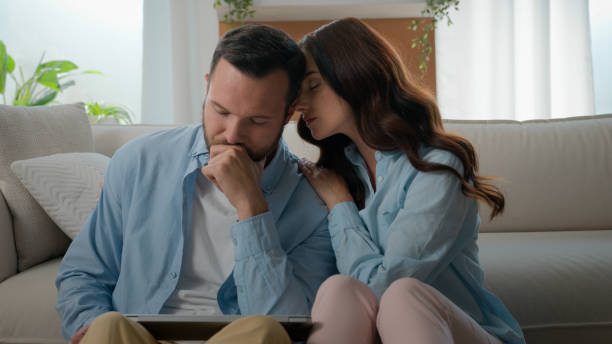 Caucasian man lost with laptop bad news receive email about work dismissal computer failure upset husband woman wife calming consoling supporting hugging lovely boyfriend couple at home family support