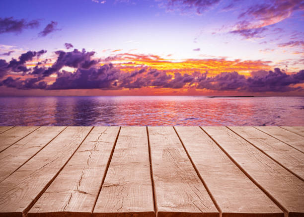 Empty wooden table top with tropical ocean sunset and dramatic sky background