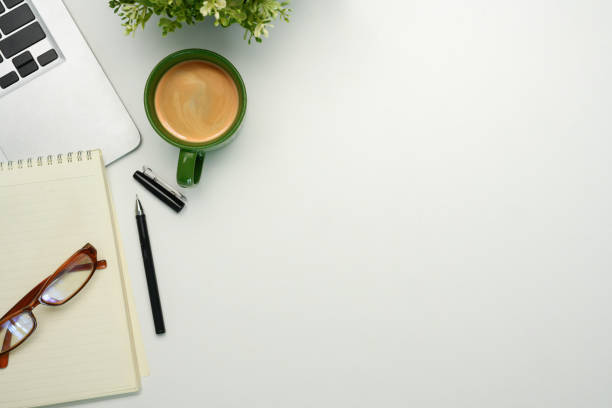 Minimalist workspace with coffee cup and notebook, glasses and laptop