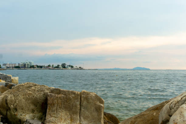 A serene coastal view featuring rocky formations by water, with distant shoreline and soft pastel skies. tranquil atmosphere invites relaxation and reflection