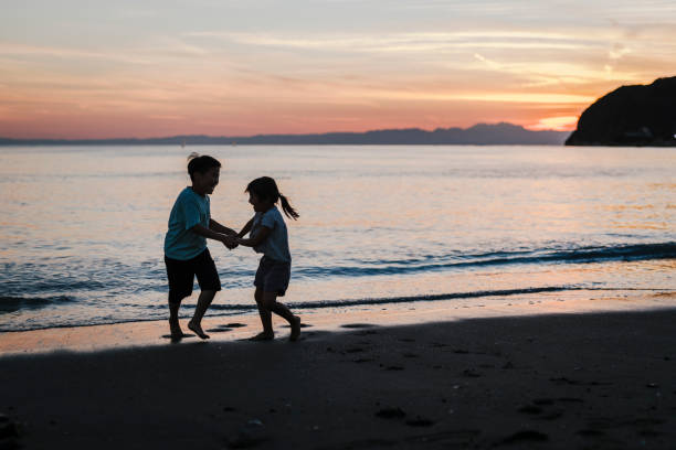 Japanese brother and sister playing in the beach at sunset.