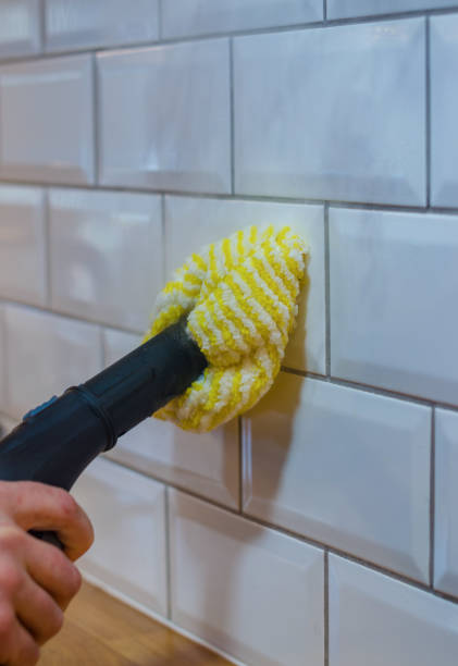 istock Man cleaning white tile wall with a yellow microfiber cloth and steam cleaner. 2190494472