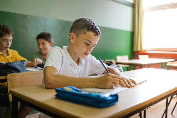 istock Students engaged in writing notes in a classroom during a sunny day, capturing a moment of focused learning and creativity 2190496902