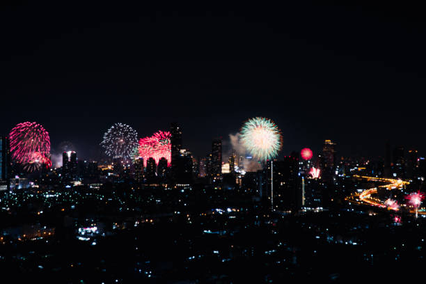 Blur background landscape thailand countdown showing flowers fireworks bright nice viewing over buildings towers city in midnight new year. Shiny light fireworks festival modern city on dark sky night
