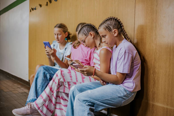 istock School students engaged with mobile phones during breaks in a hallway at school, socializing and staying connected with friends 2190497615