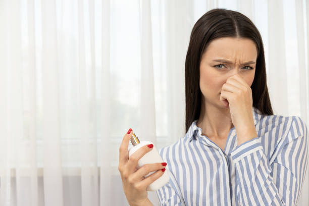 Close-Up of Mature Woman Testing Fragrance by Spraying Perfume on a White Test Strip in a Cosmetic Store Environment