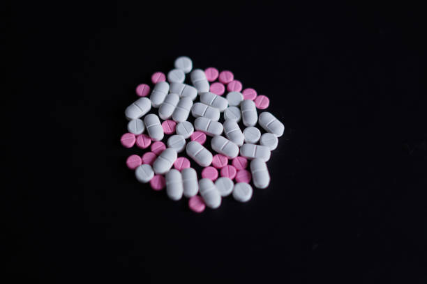 istock pink and white pills on black background 2190499824