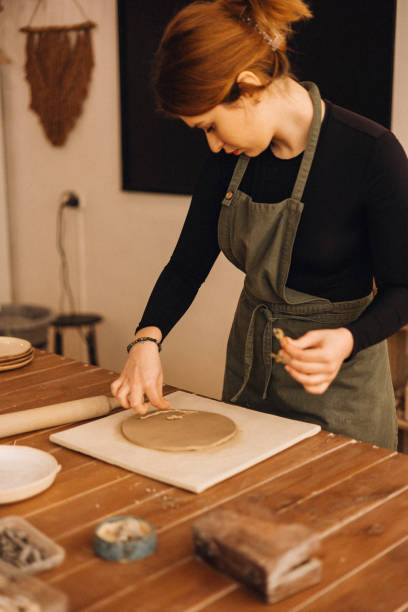 istock Young woman decorating clay blank by dry plants 2190501453