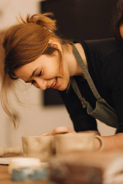 istock Smiling woman carefully makes a cup from clay at the cozy pottery workshop 2190501761
