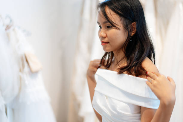 istock Bride Adjusting Satin Off-Shoulder Wedding Dress with Soft Lighting 2190502300