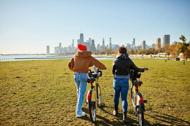 istock Eco-friendly women walking bikes across public park lawn 2190502576