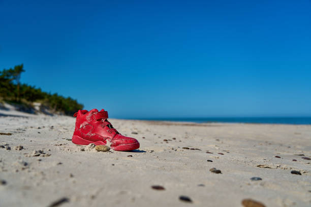 bright red shoe on a sand dune at a beautiful beach in Slowinski National Park along the coast of the baltic sea in Leba, Pomerania, Poland.