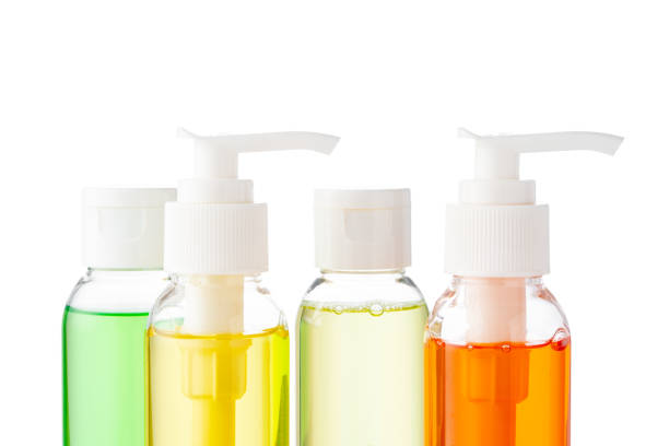 Various bottles with colored liquids and pumps arranged on white background for beauty